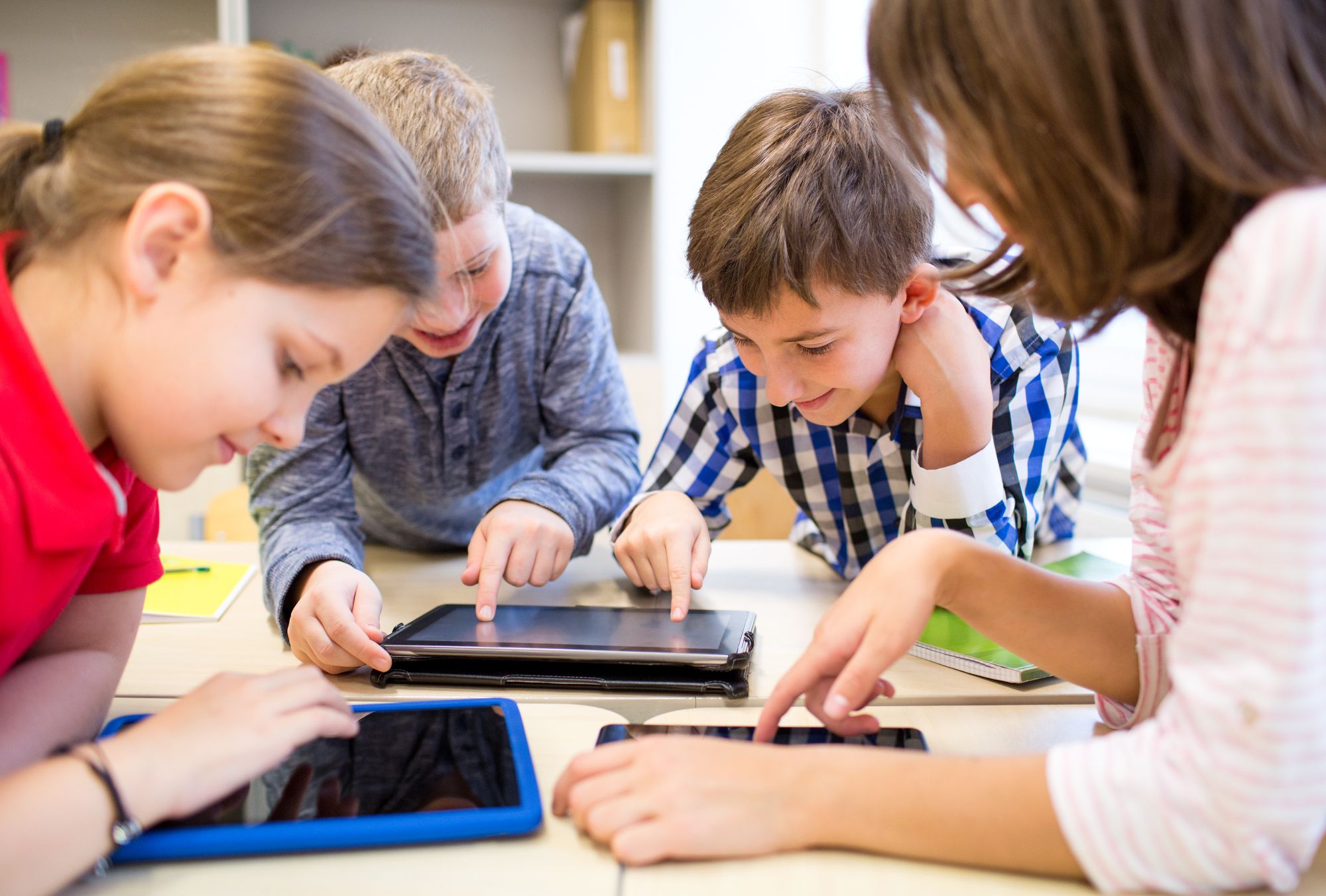 group of young kids playing on ipads and tablets