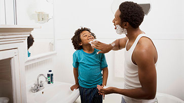African American Father shaving putting shaving cream on young child